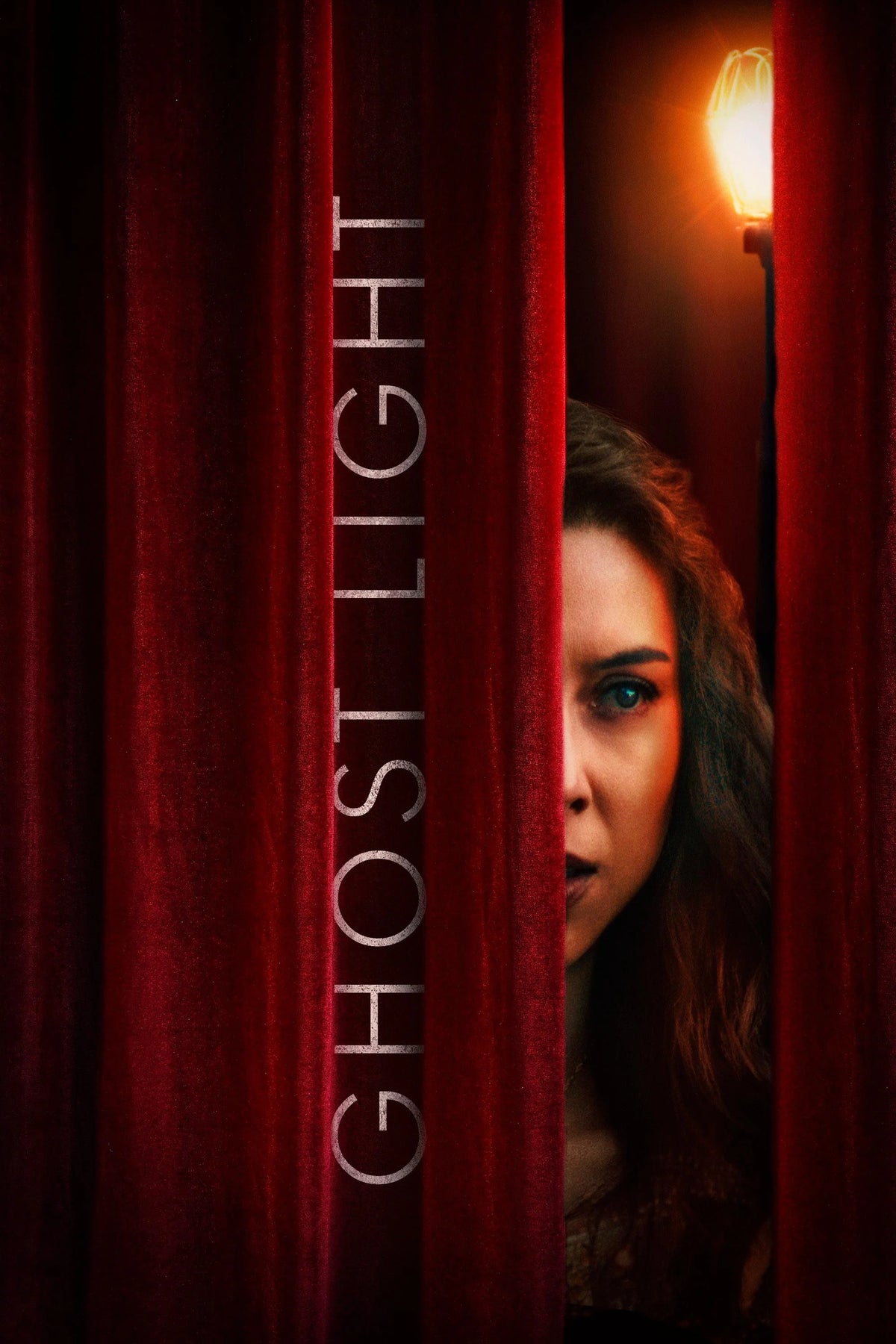 Ghost Light poster with a woman peering from behind red theater curtains